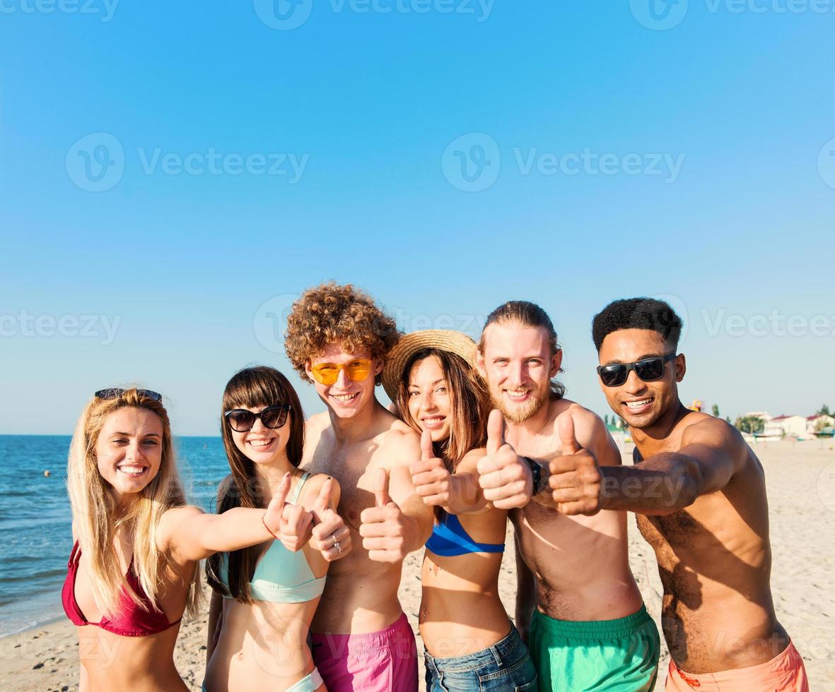 Group of friends having fun on the beach. Concept of summertime photo