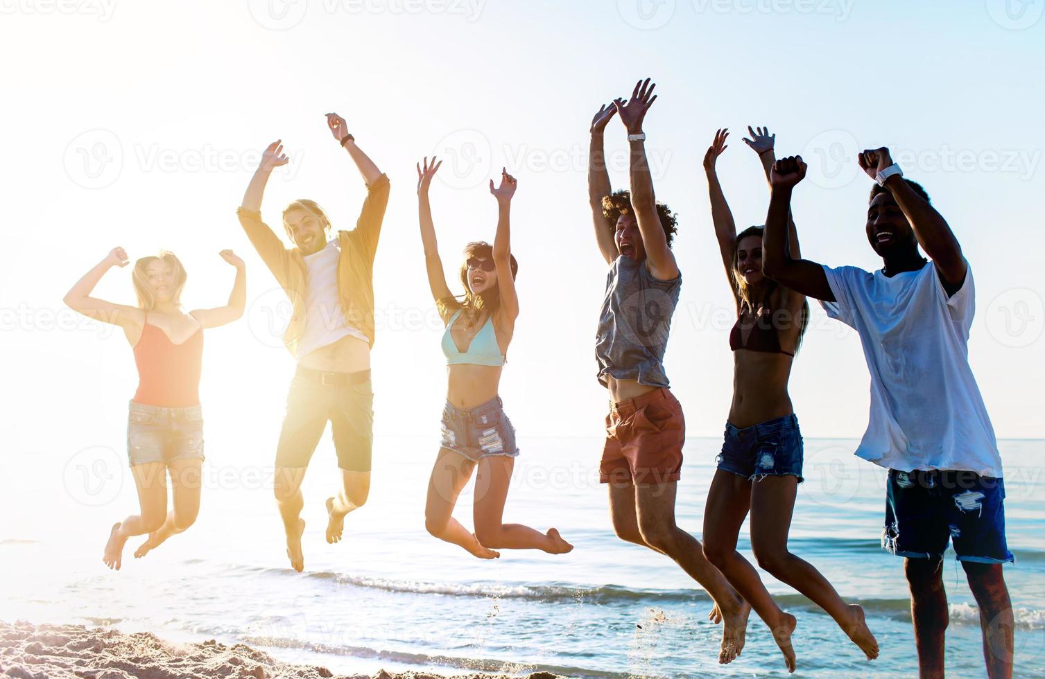 Happy smiling friends jumping at the beach photo