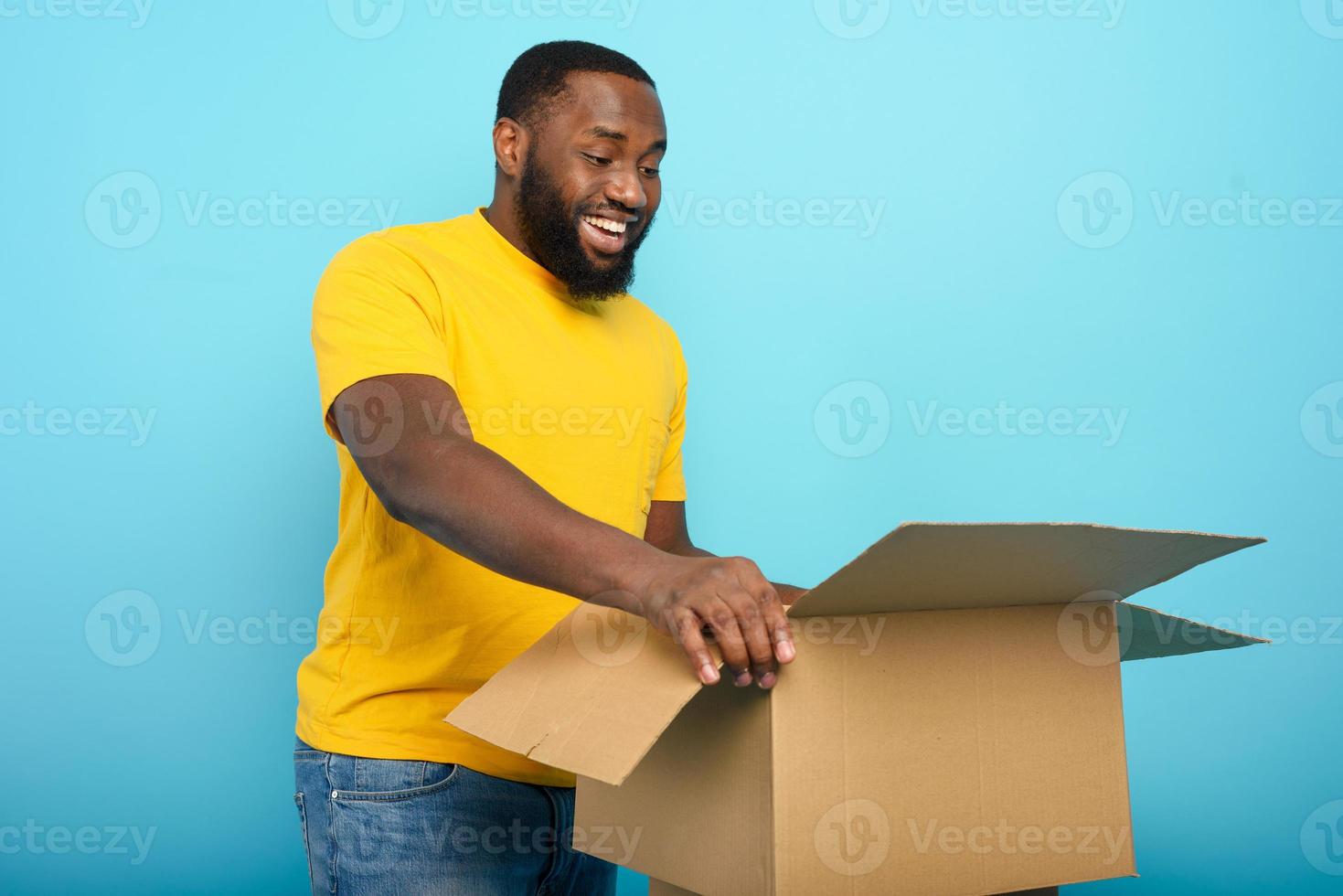Happy man receives a package from online shop order. happy expression. Blue background. photo