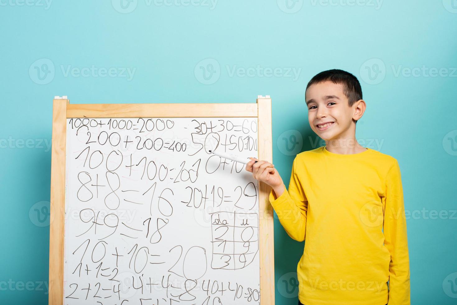 Child solves mathematical problem with abacus. Cyan background photo