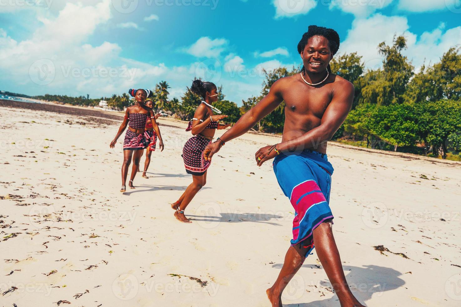 Local group of people with typical kenyan clothes dancing on the beach photo