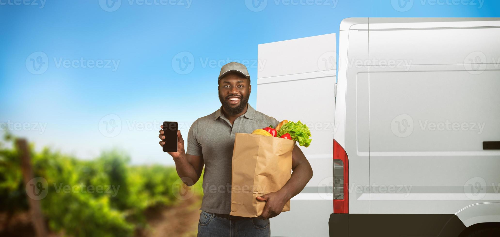 Delivery guy with a grocery bag full of food with the vegetable garden from which the products arrive photo