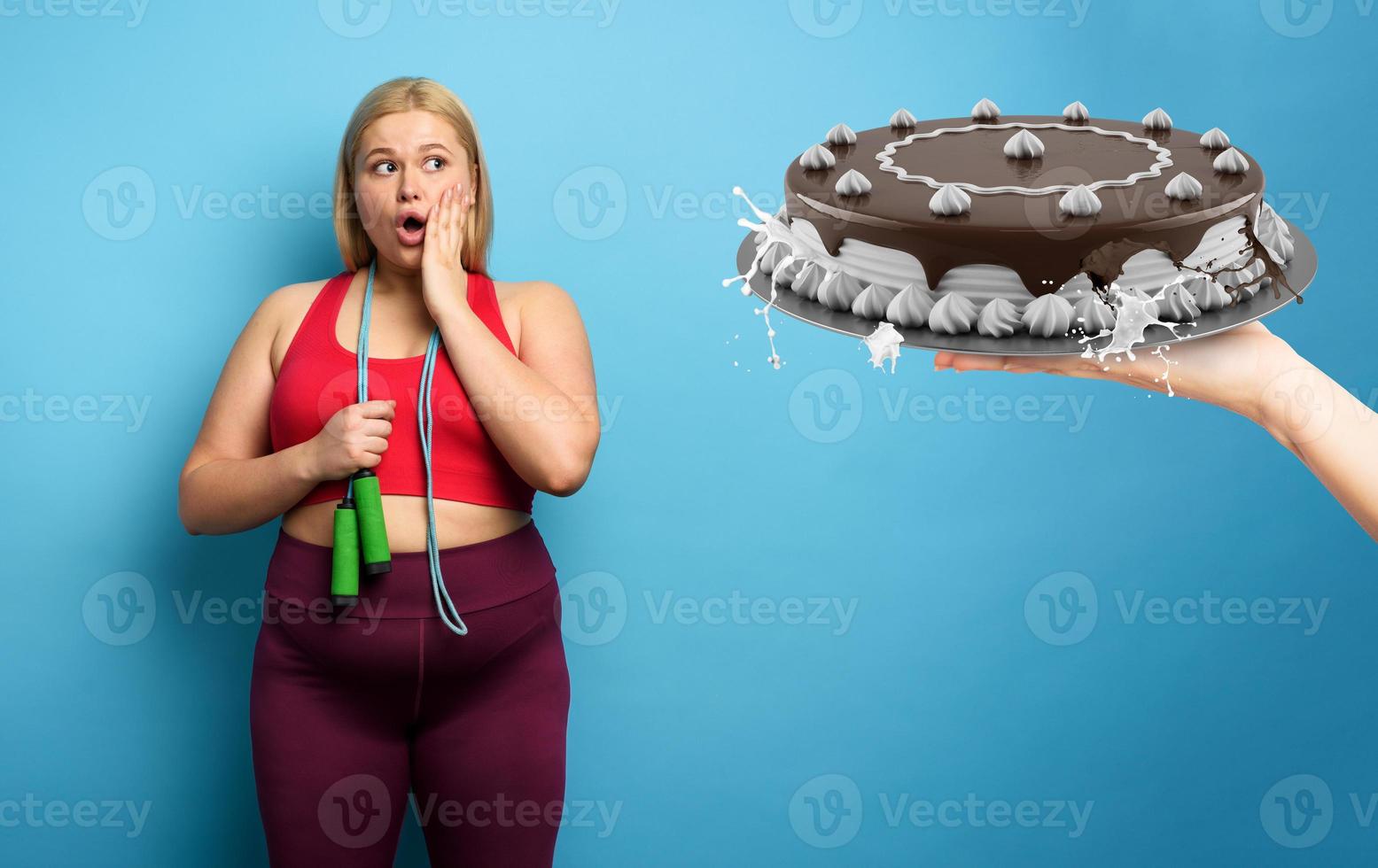 Fat girl does gym but she wants to eat a big cake. cyan background photo