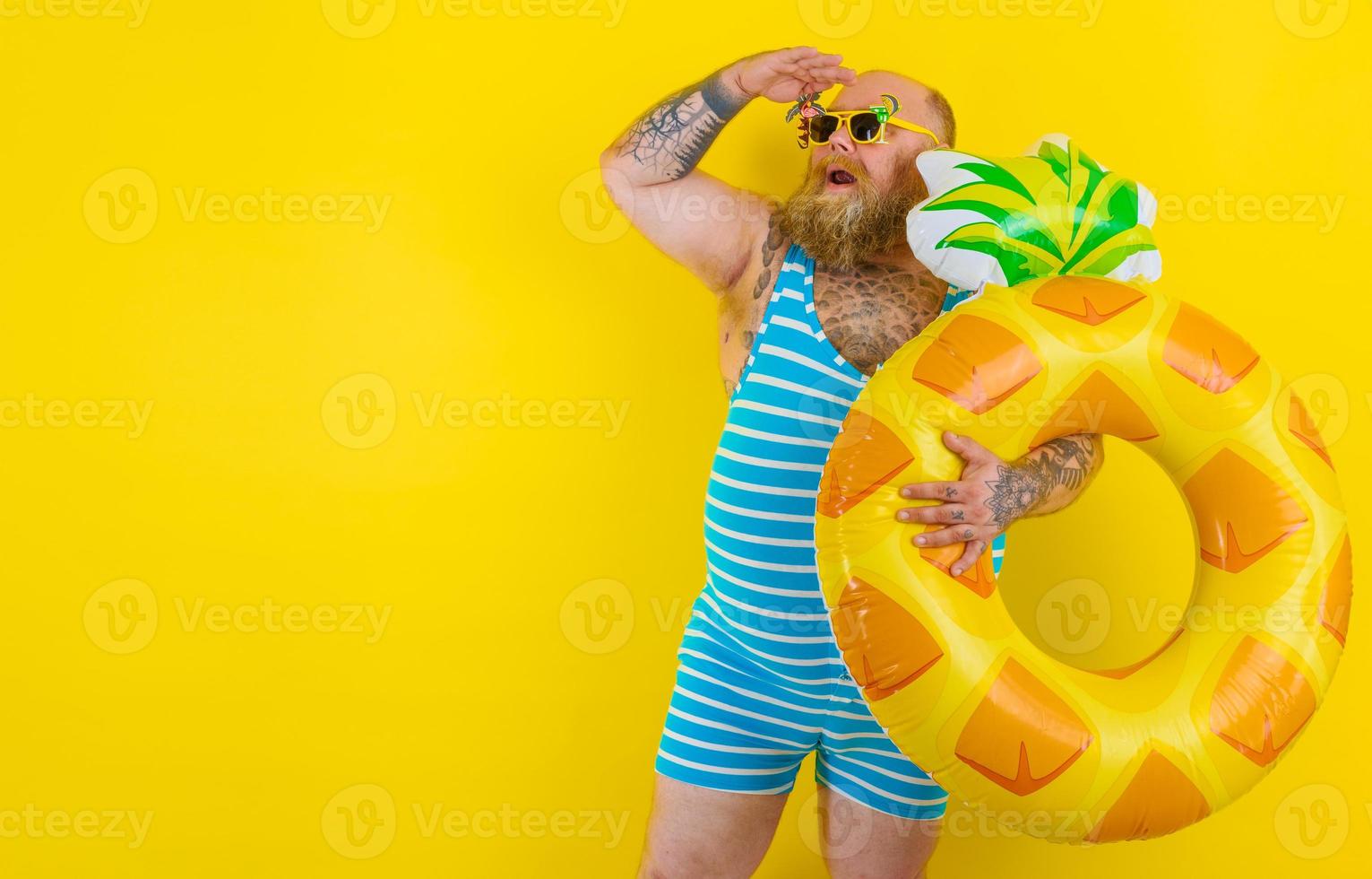 Fat amazed man with wig in head is ready to swim with a donut lifesaver photo