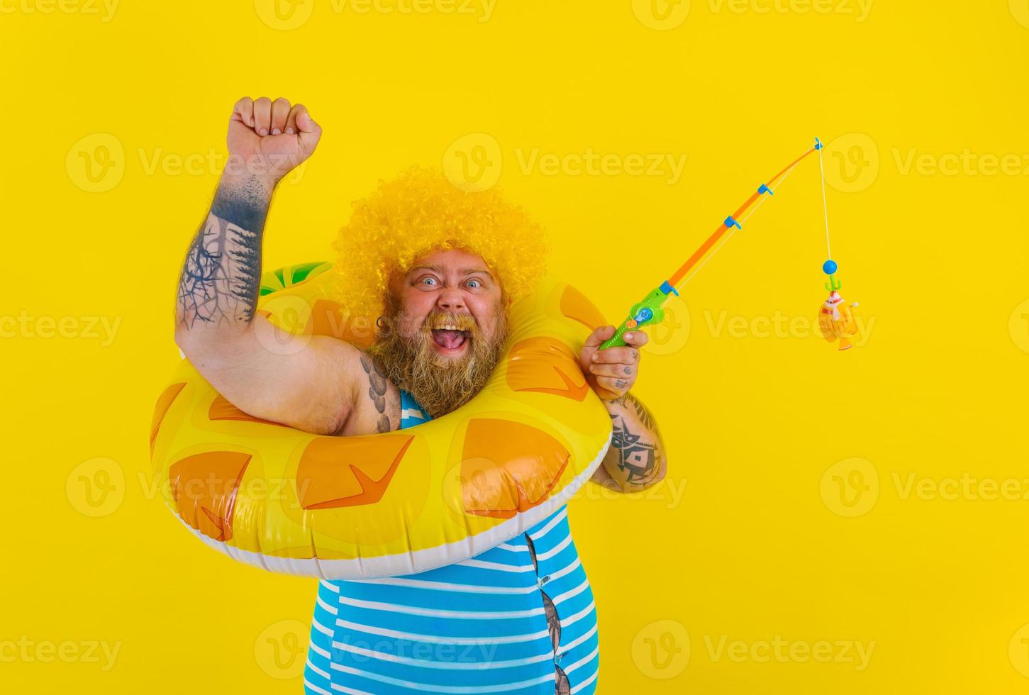 Fat happy man with wig in head plays with the fishing rod photo