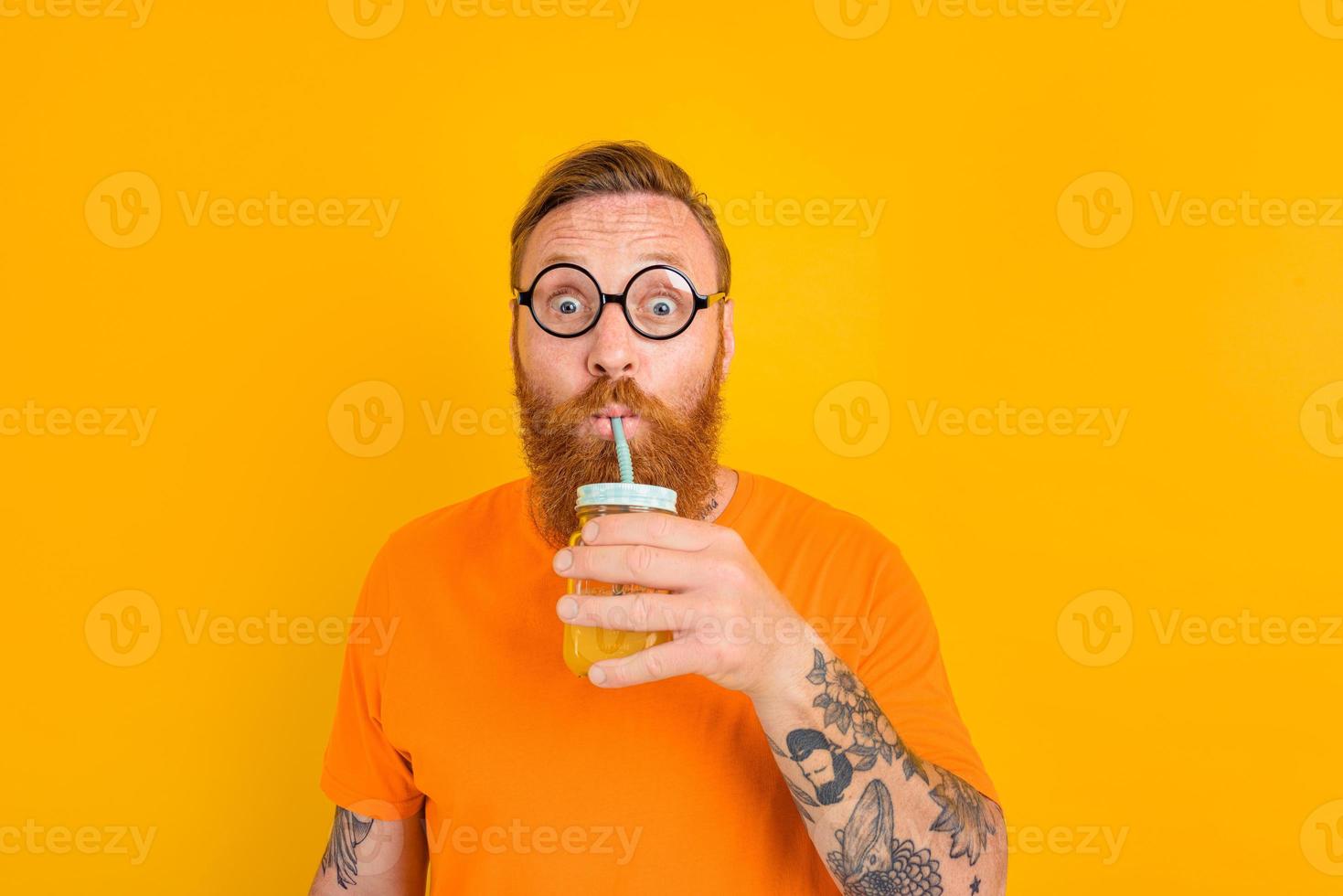Nerd amazed man with glasses drinks a fruit juice photo