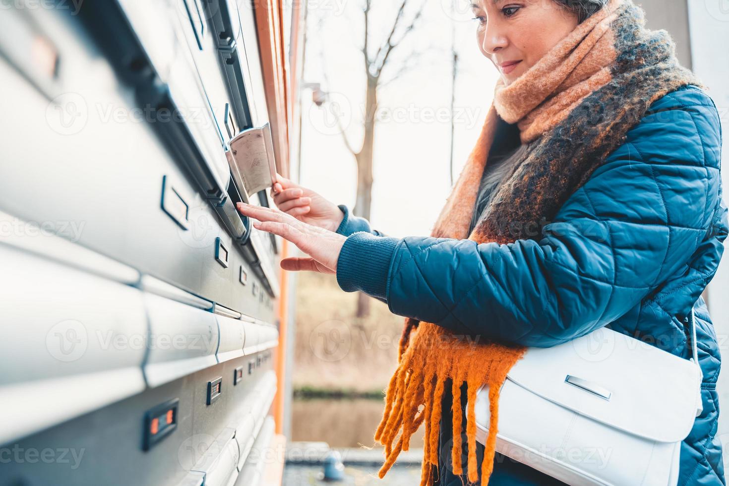 Senior woman opens the mailbox to check for new mails photo
