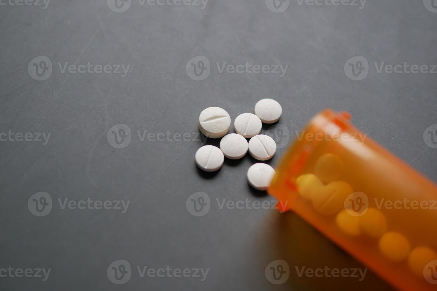 white color medical pills spilling on gray background photo