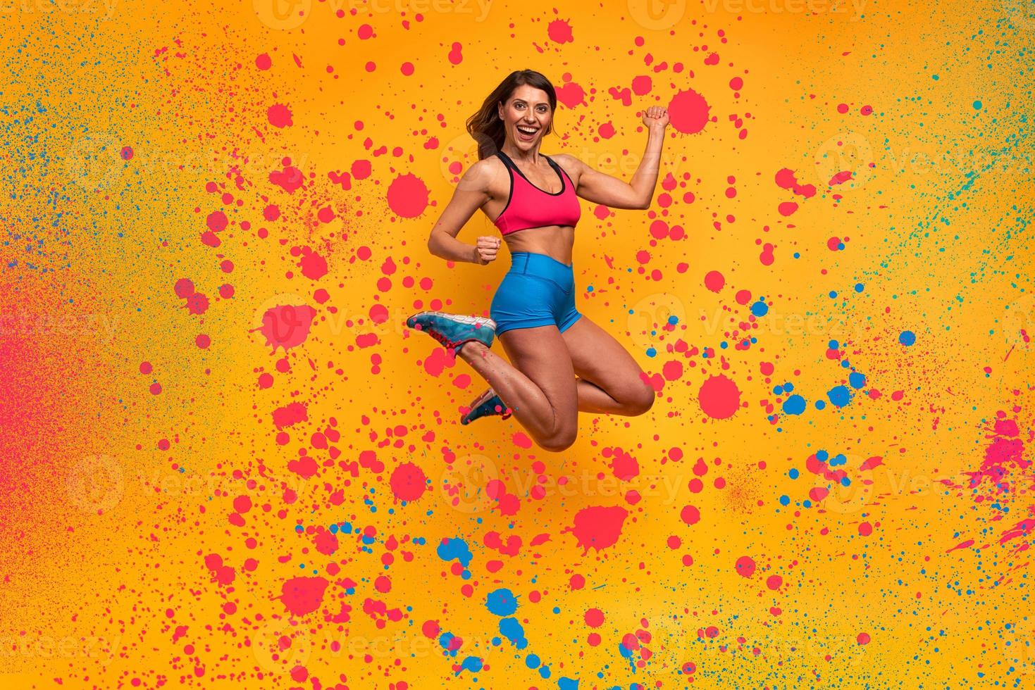 Sport woman jumps on a yellow background. Happy and joyful expression. Spray effect photo