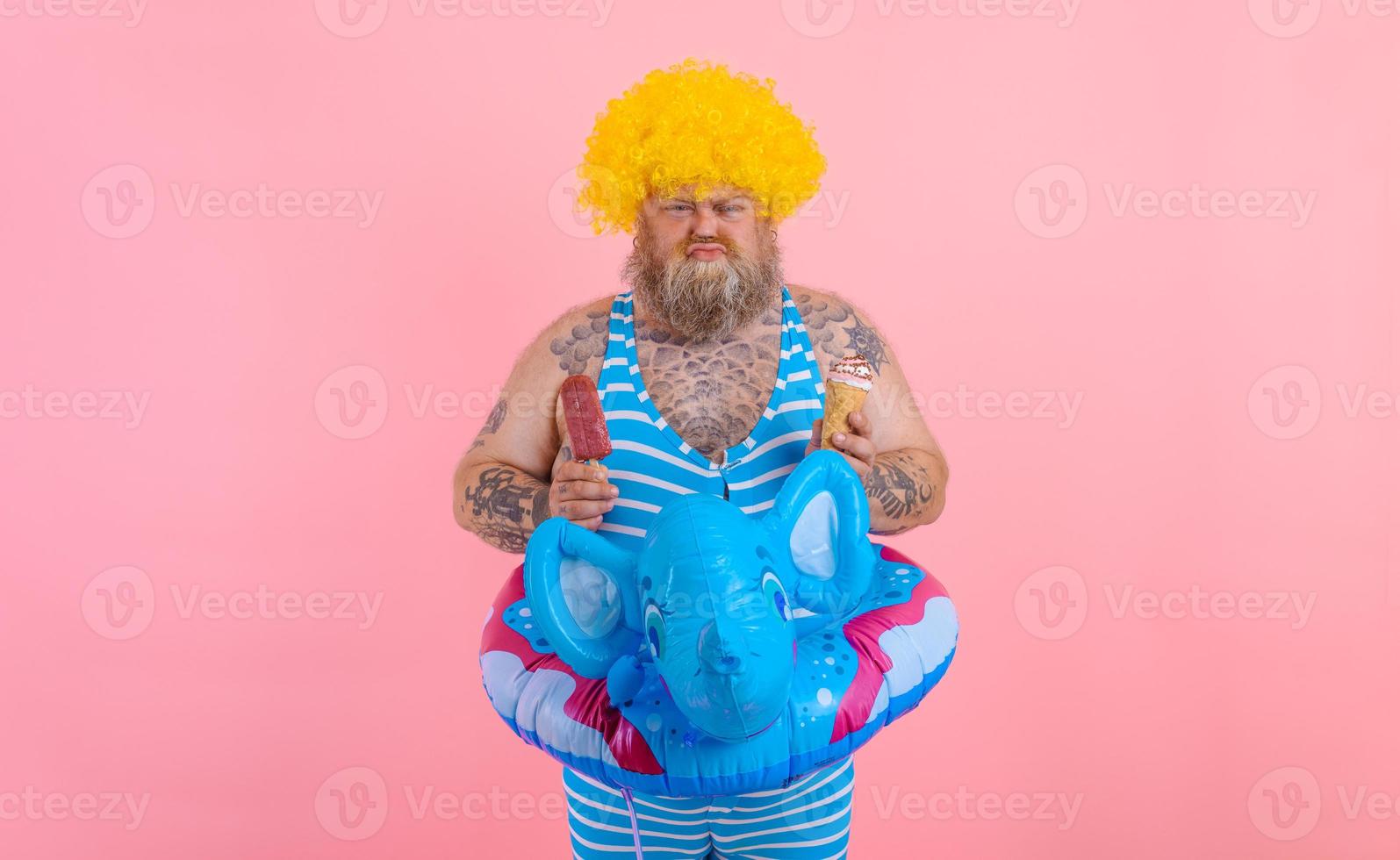 Fat man with beard and wig eats a popsicle and an icecream photo