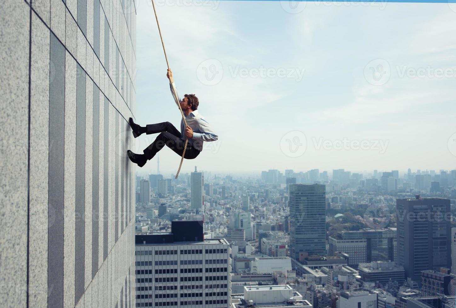 Businessman climbs a building with a rope. Concept of determination photo