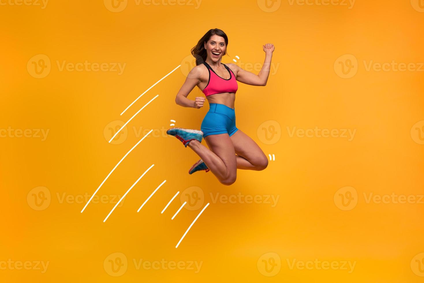Sport woman jumps on a yellow background. Happy and joyful expression. photo