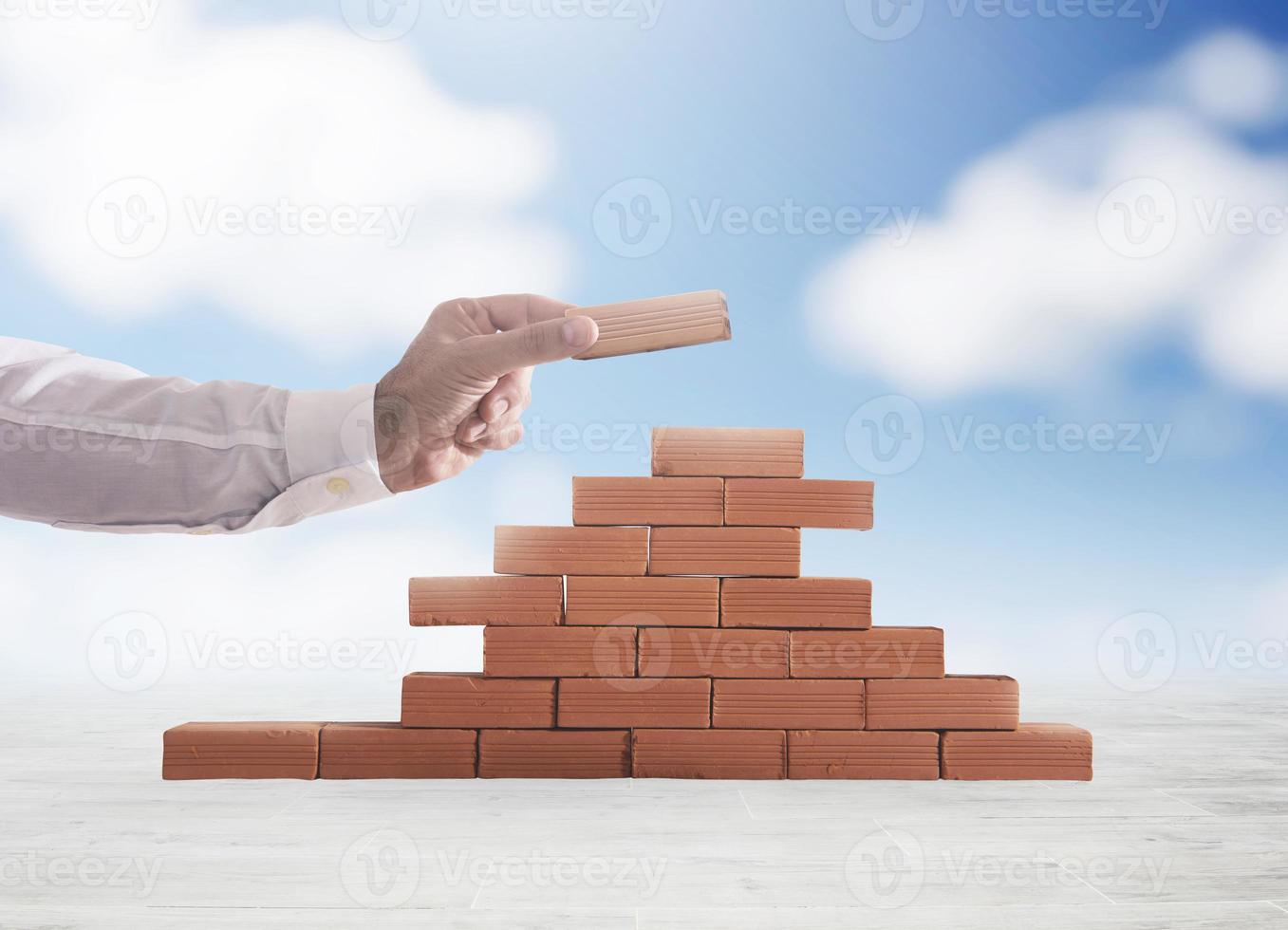 Businessman puts a brick to build a wall. Concept of new business, partnership, integration and startup photo