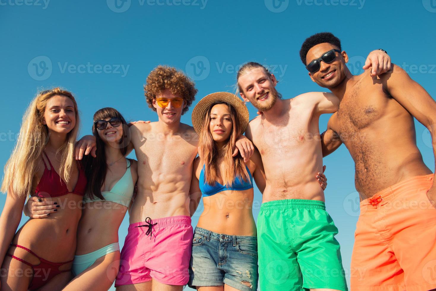 Group of friends having fun on the beach. Concept of summertime photo