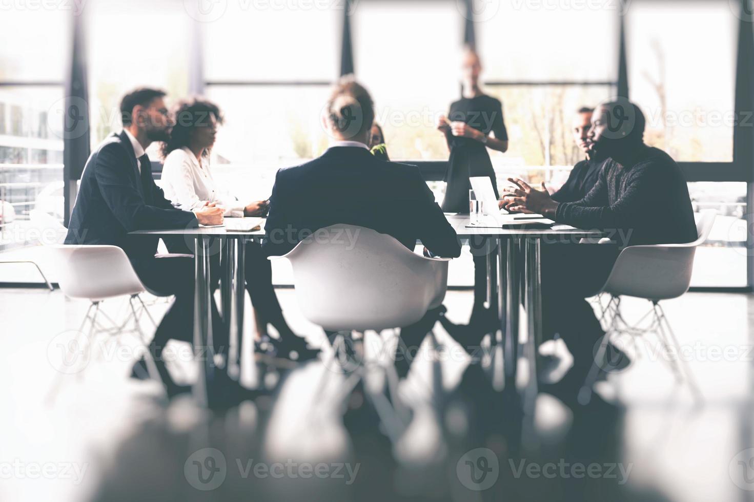 Background concept with business people sitting at the meeting table in the office near a window glass photo