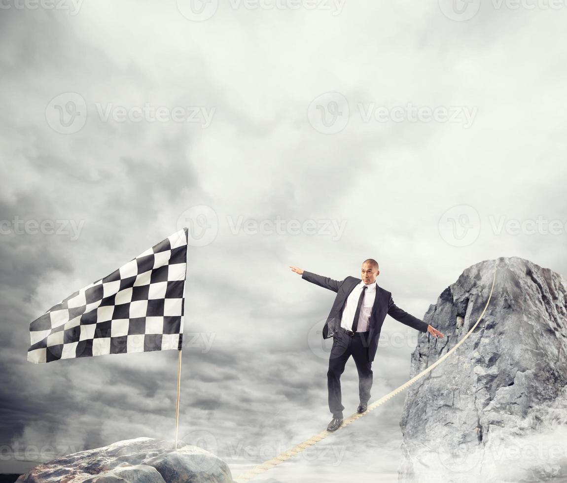 Business concept of businessman who overcome the problems reaching the flag on a rope photo