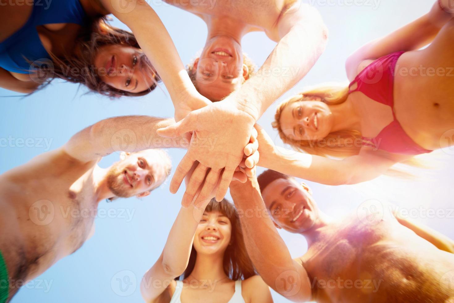 Happy group of friends give five in circle under the sun photo