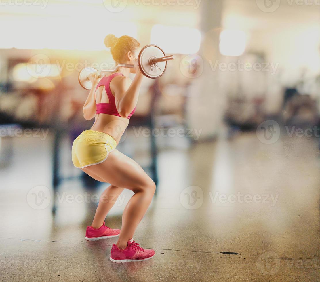 Athletic girl works out at the gym with a barbell photo