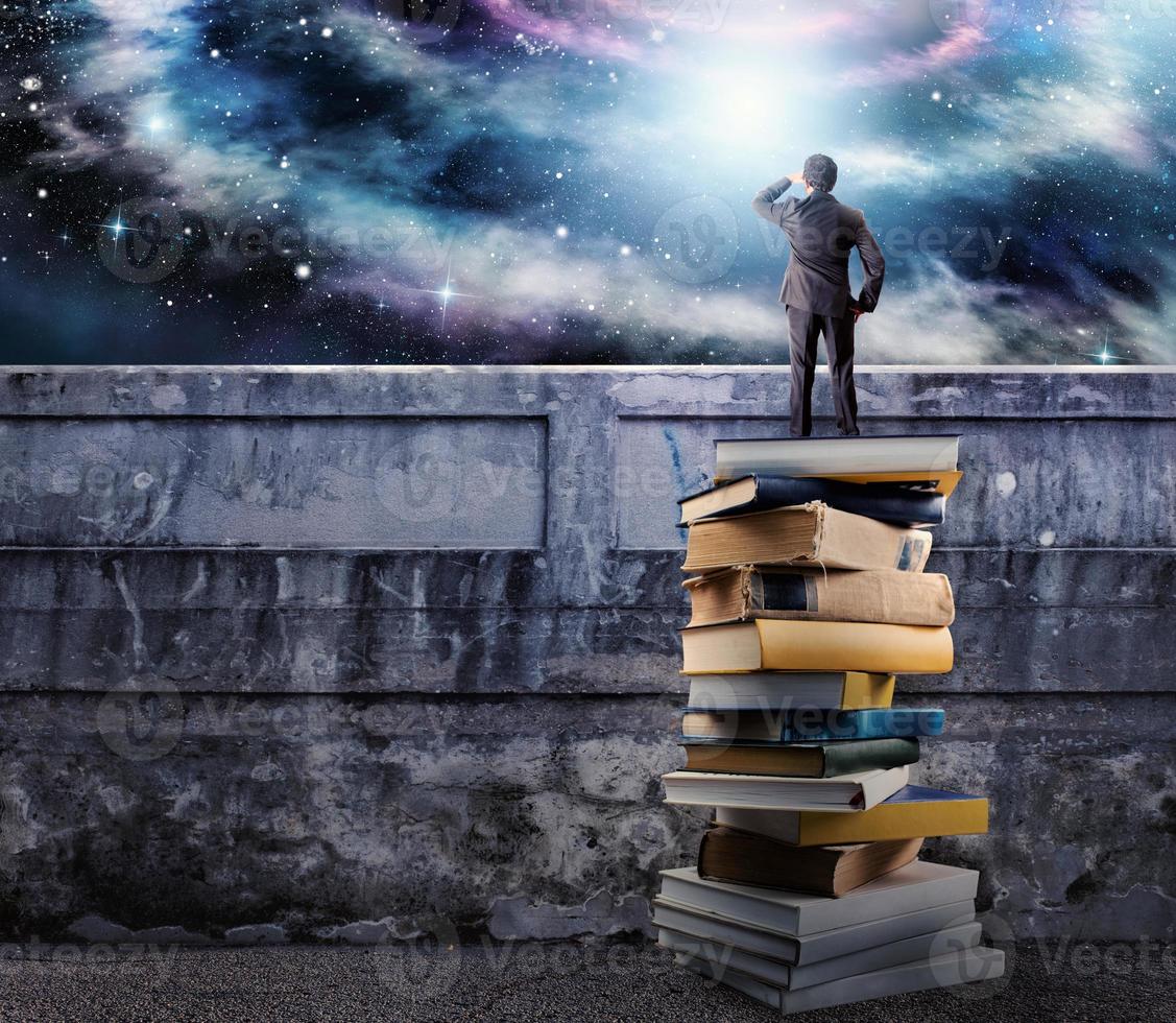 Businessman over a pile of books observe the universe full of sky. the culture open the imagination photo