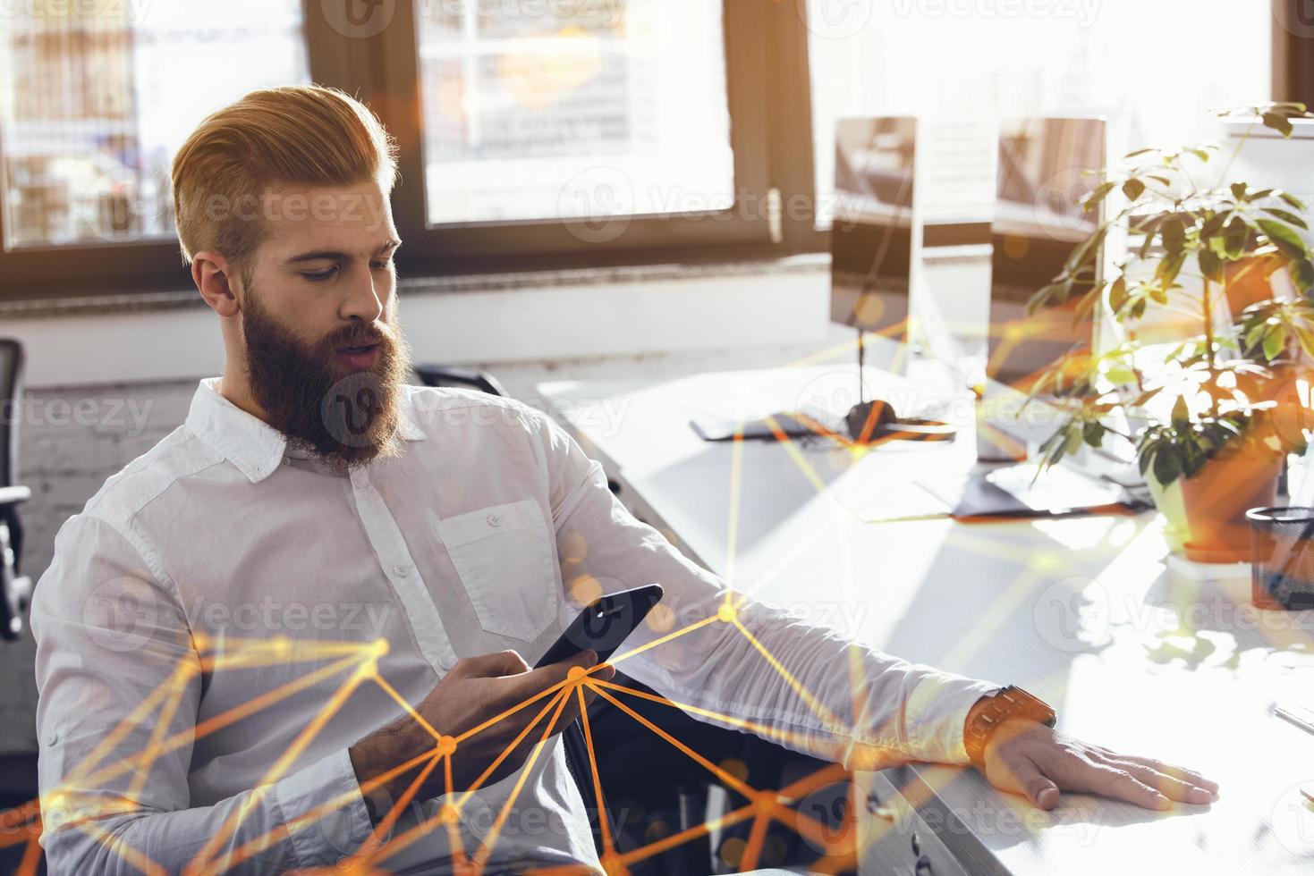 Businessman touching cellphone in office during work photo