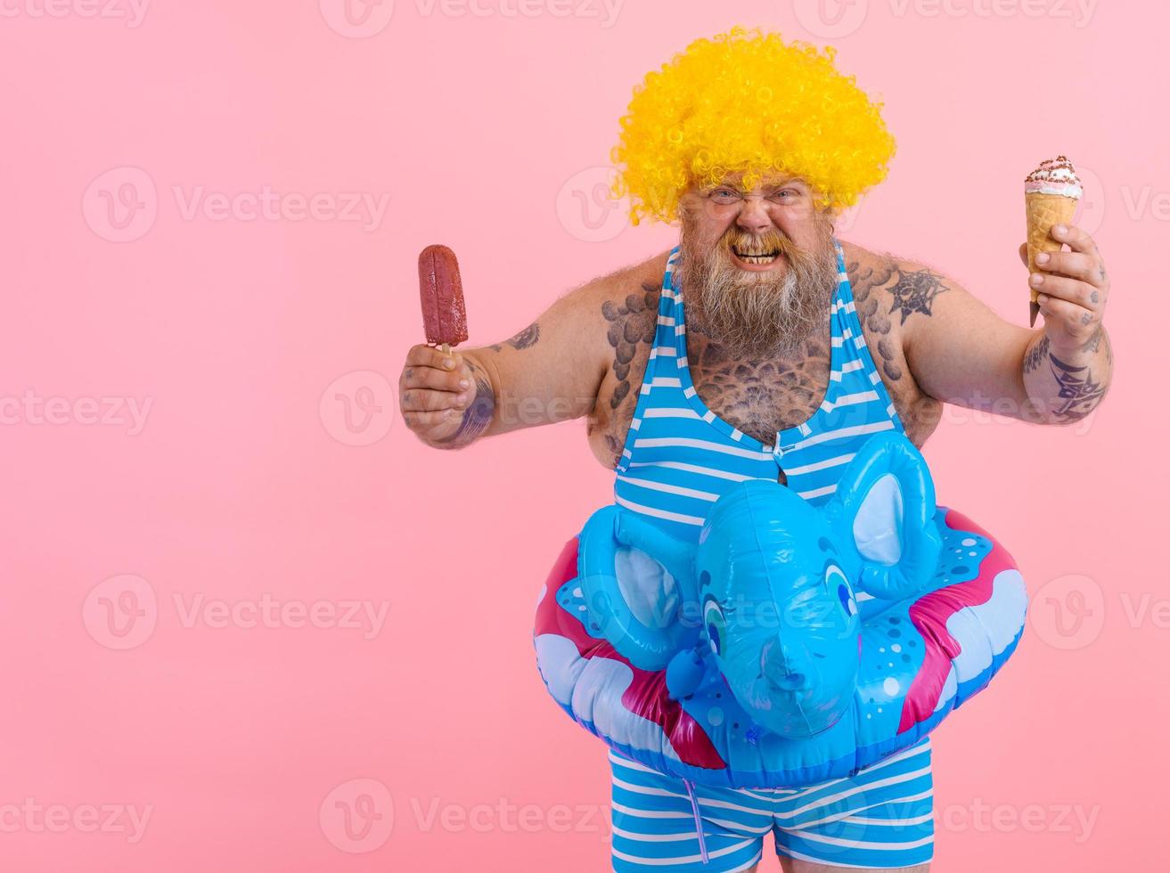 Fat man with beard and wig eats a popsicle and an icecream photo