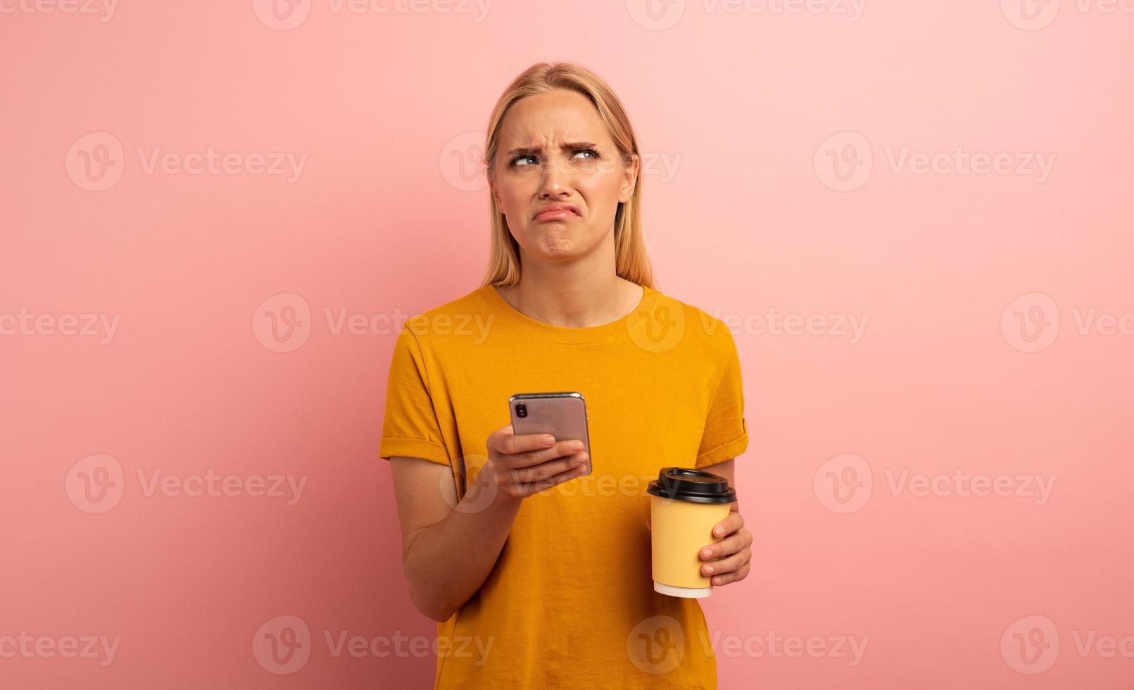 Blonde girl thinks about the right option. Yes or no. Confused and pensive expression. Pink background photo