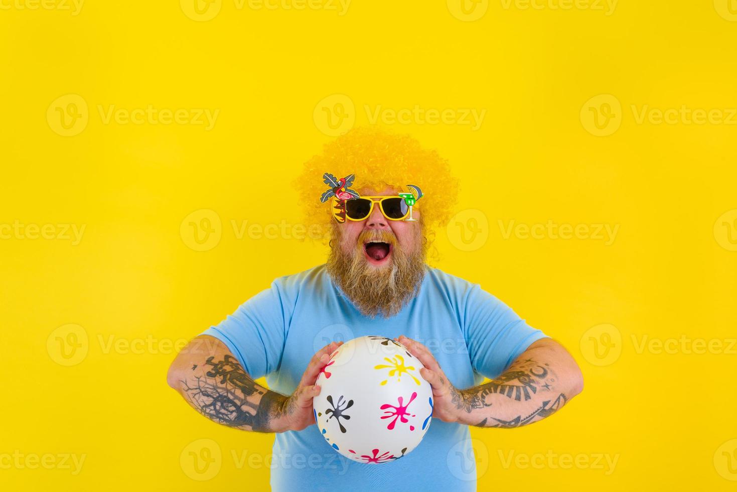 Fat man with wig in head and sunglasses have fun with a ball photo