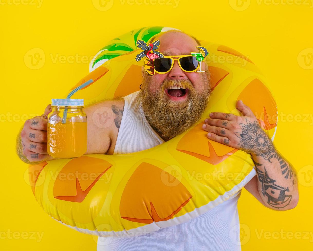 Fat happy man with wig in head is ready to swim with a donut lifesaver photo
