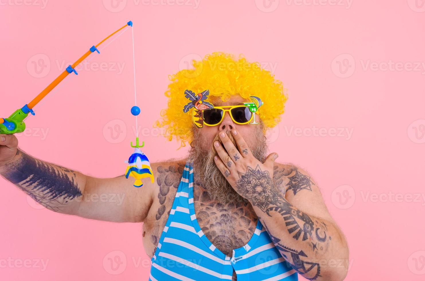 Fat amazed man with beard and sunglasses have fun with the fishing pole photo