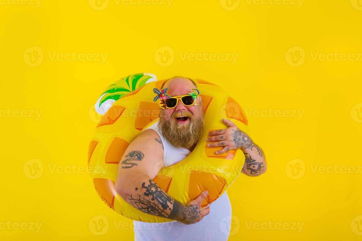Fat happy man with wig in head is ready to swim with a donut lifesaver photo