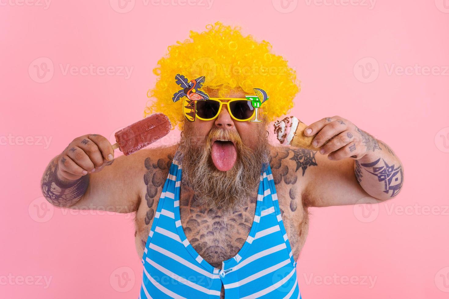 Fat man with beard and wig eats a popsicle and an icecream photo