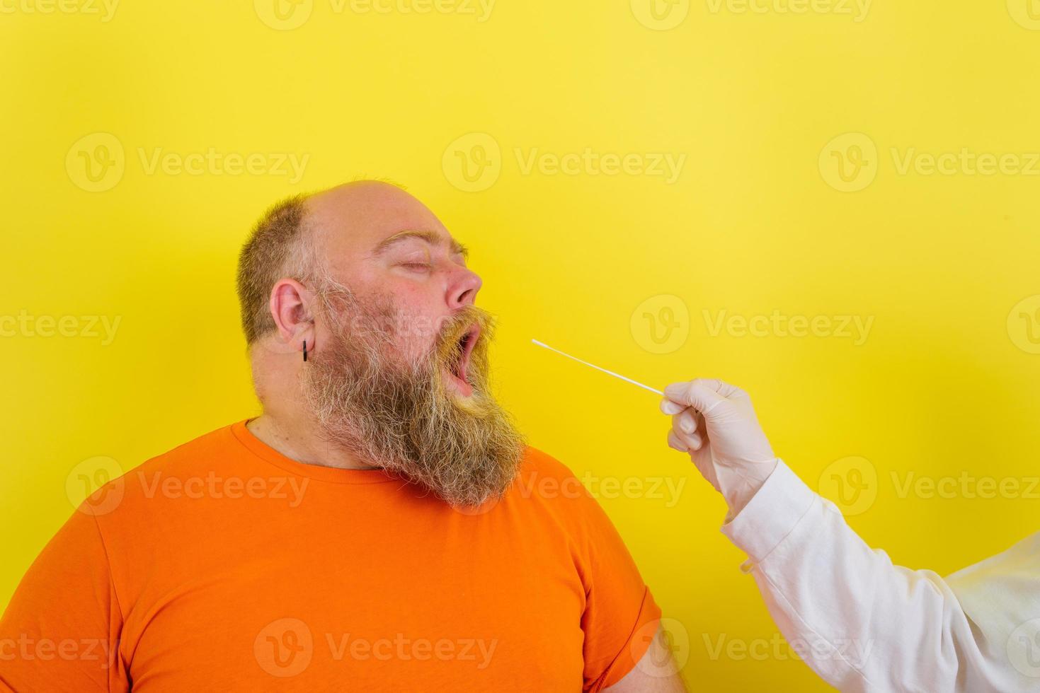 man with beard and tattoos does the covid-19 test photo