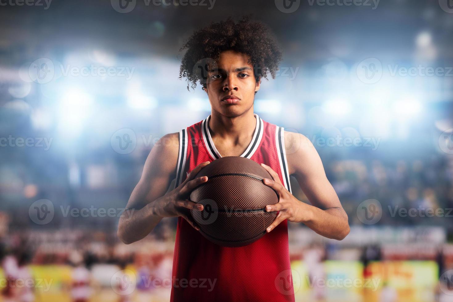 Basketball player holds the ball in the basket in the stadium full of spectators. photo