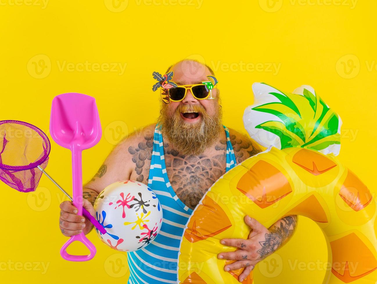 Fat happy man with wig in head is ready to swim with a donut lifesaver photo