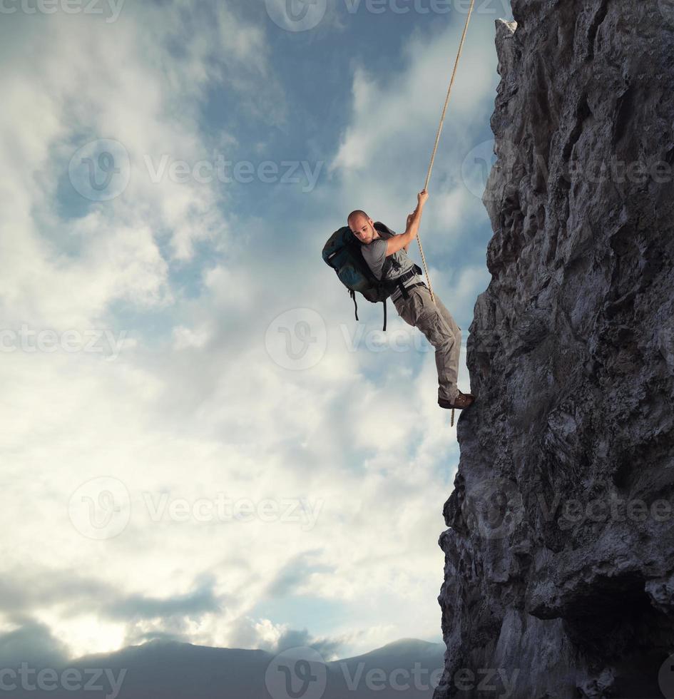 Man climbs a high danger mountain with a rope photo