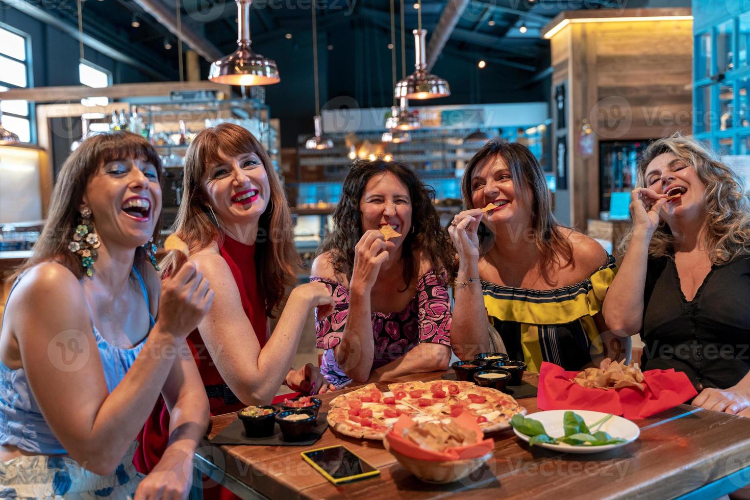 grupo de maduro mujer sentado en un pub mientras comiendo Pizza y Bebiendo cerveza foto