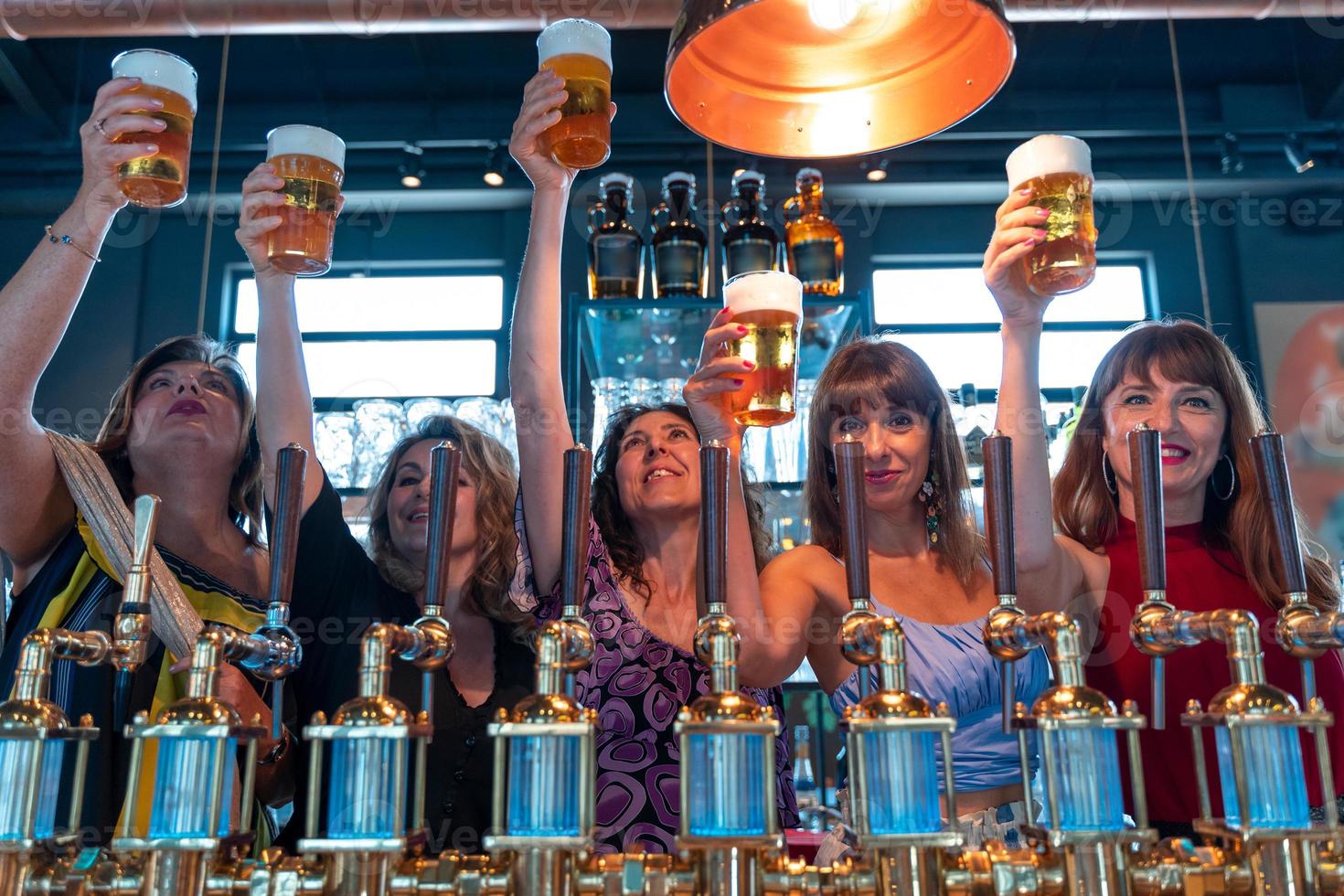 group of mature women is drinking beer in a pub in front of a beer tap photo