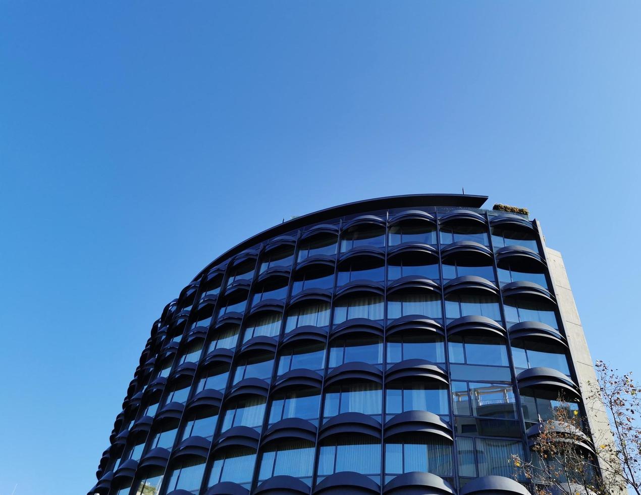 un moderno edificio cuyo ventanas reflejar el azul cielo foto