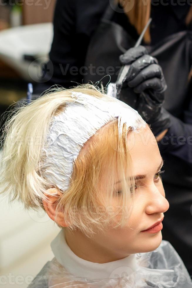 Stylist applies white dye to hair photo