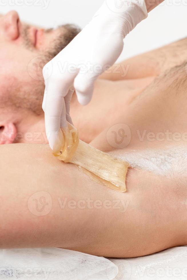 cosmetóloga aplicando pasta de cera en la axila masculina foto