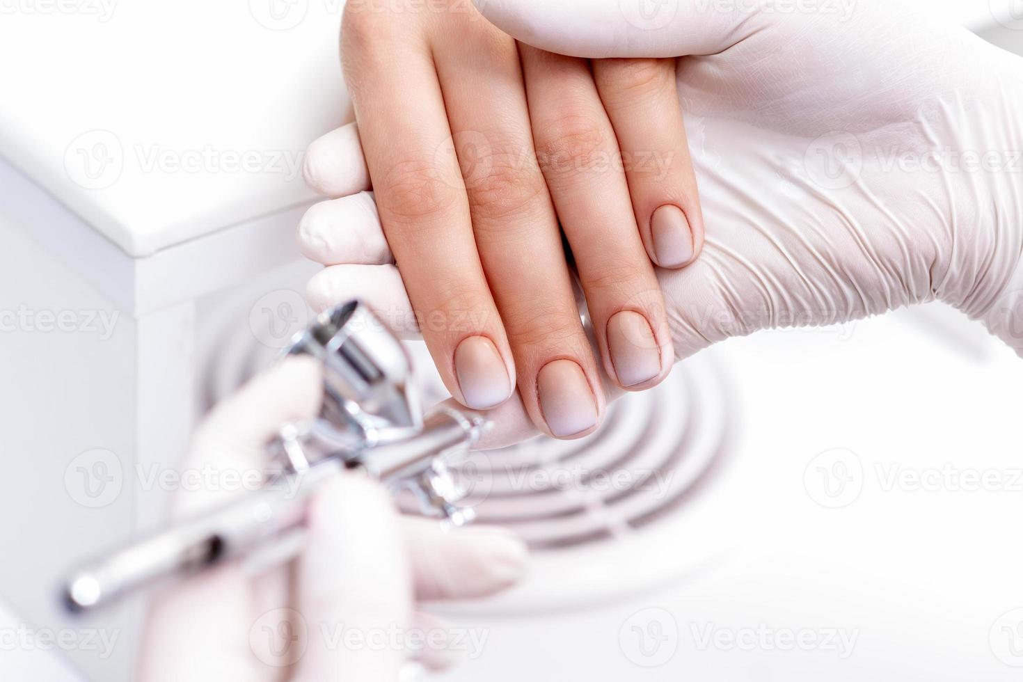 Woman receiving manicure by airbrush photo