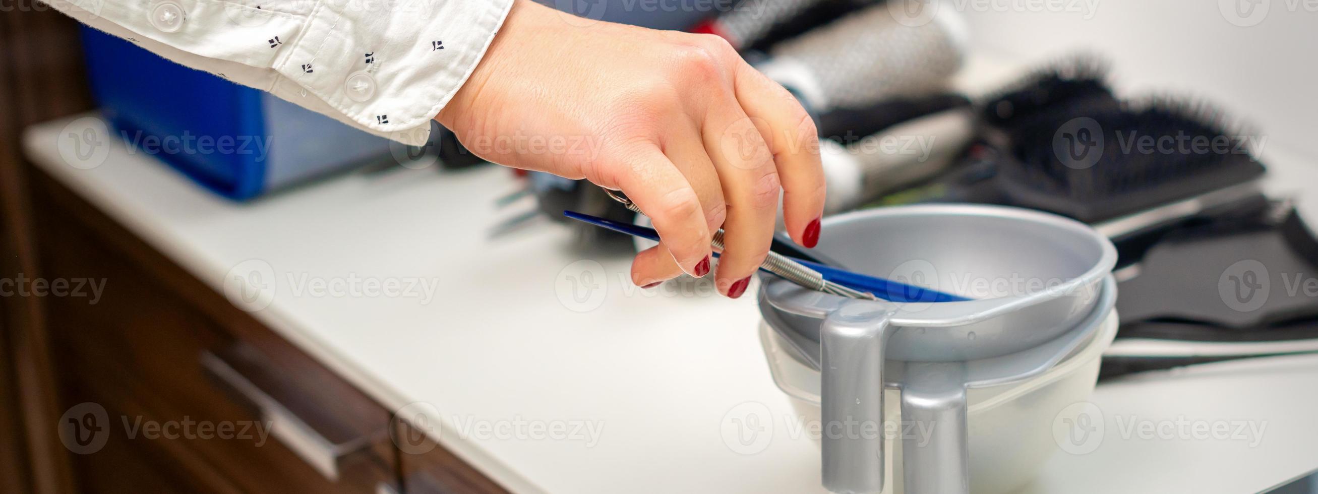 Hand of hairstylist prepares dye in bowl photo