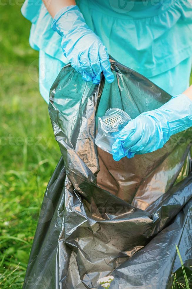 niño recoge basura plástica de la hierba foto