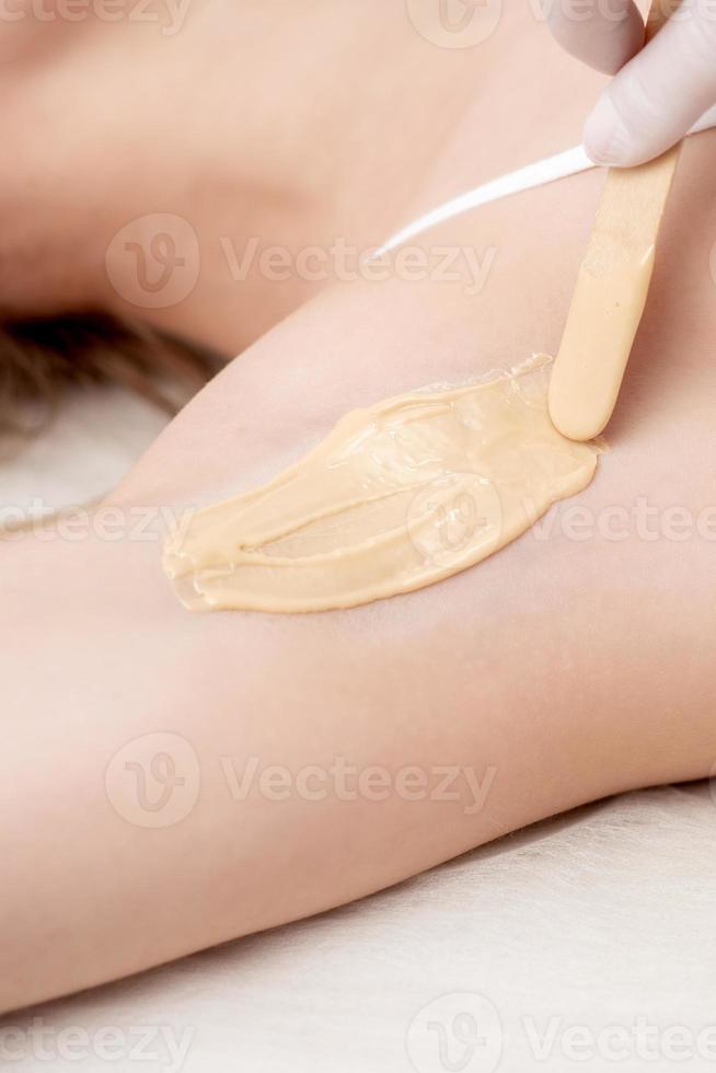 Cosmetologist applying wax paste on armpit photo