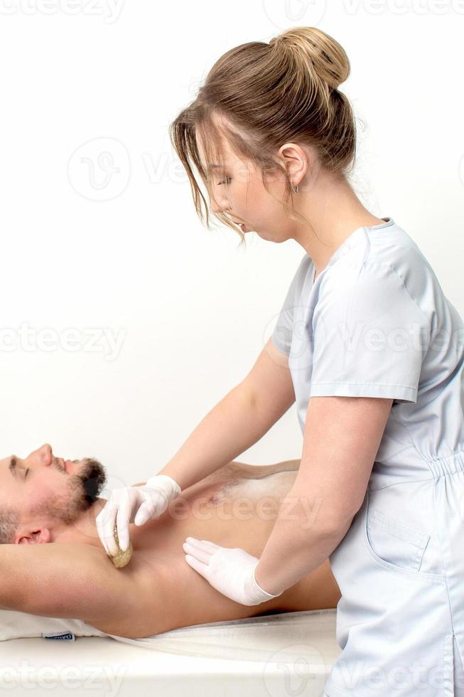Young man receiving waxing underarm photo