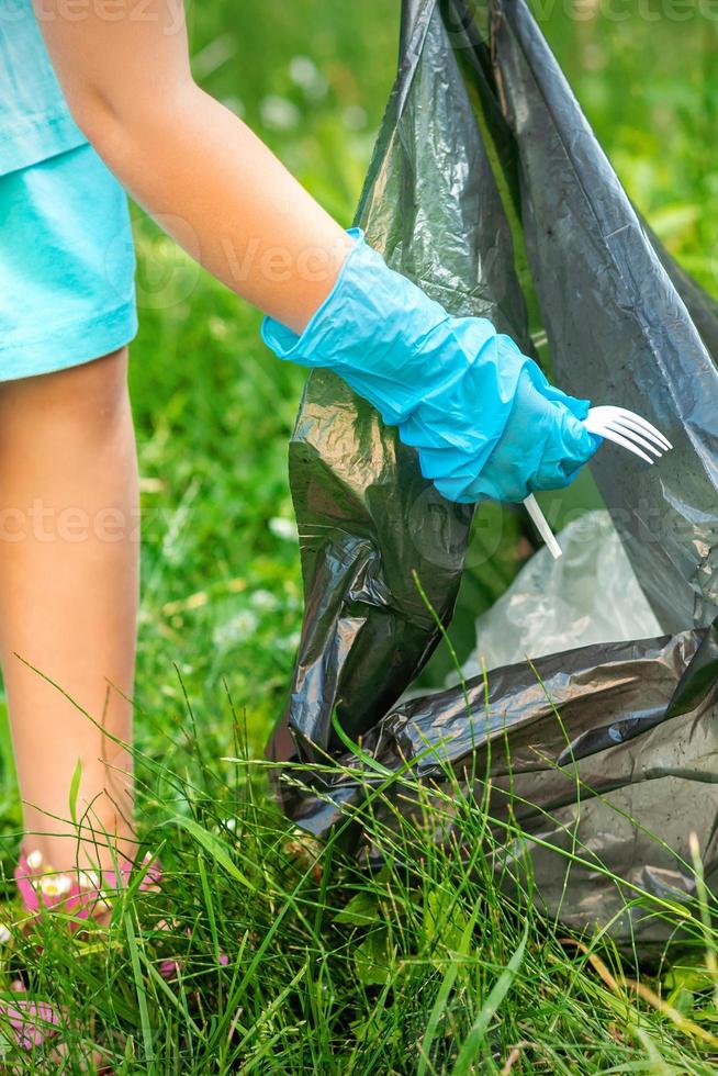 Child picks plastic trash from grass photo