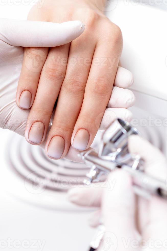 Woman receiving manicure by airbrush photo