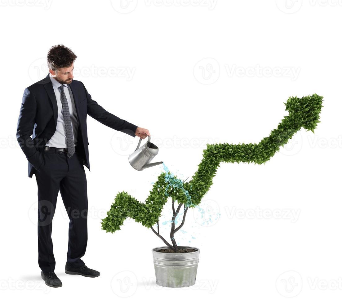 Businessman that watering a plant with a shape of arrow. Concept of growing of company economy . photo