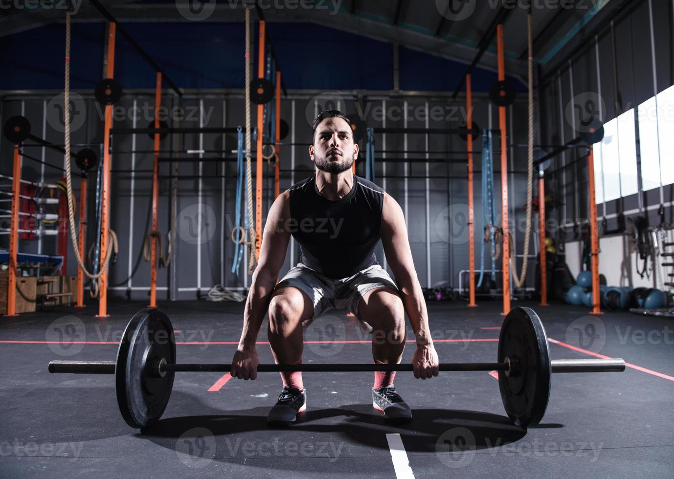 Athletic man works out at the gym with a barbell photo