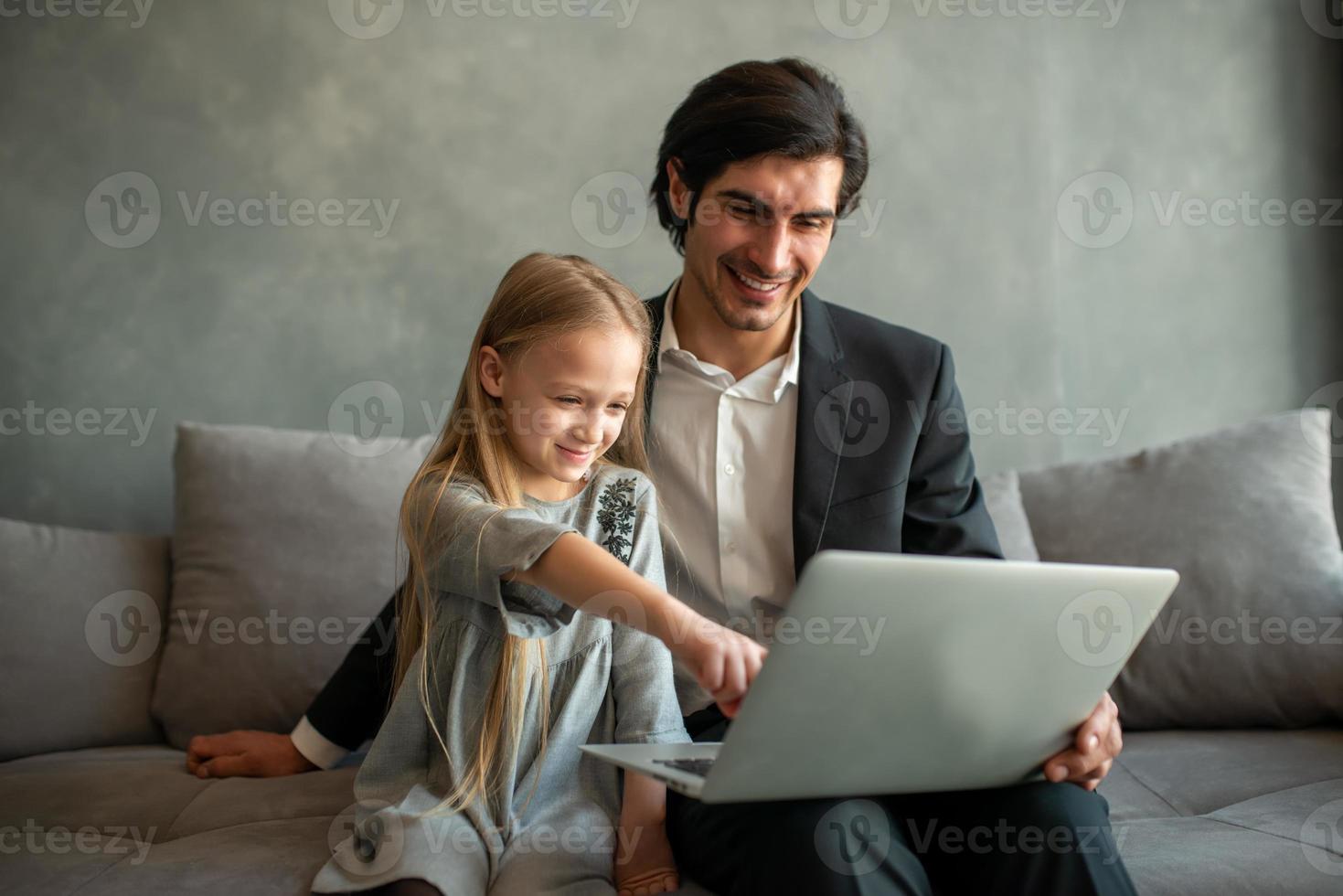 Happy little girl watching a movie on the computer with her father photo